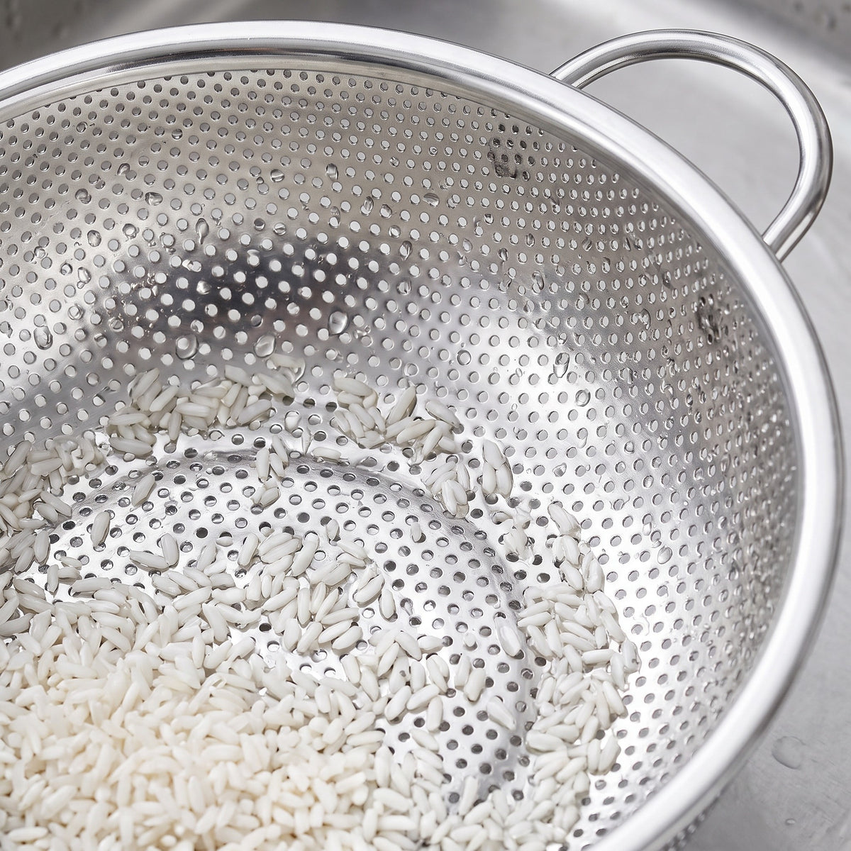 10-Inch Micro-Perforated Stainless Steel Colander for Grains - close-up of the micro-perforations holding rinsed rice