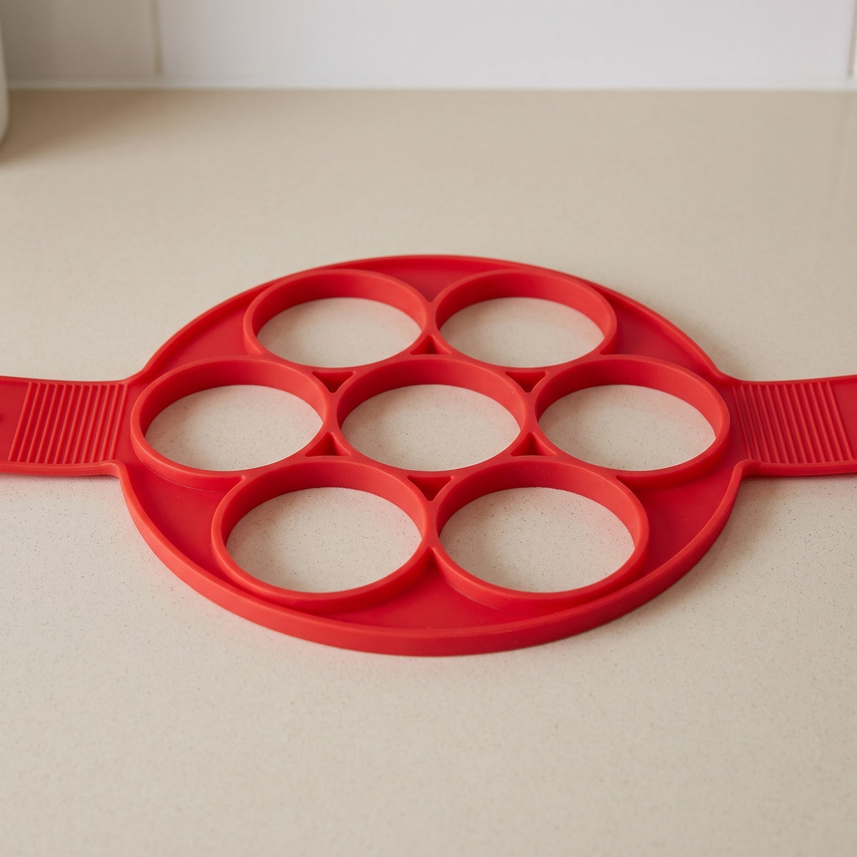 2-in-1 Non-Stick Silicone Pancake Mold for Stovetop and Oven - close-up of the red silicone rings and ribbed handles