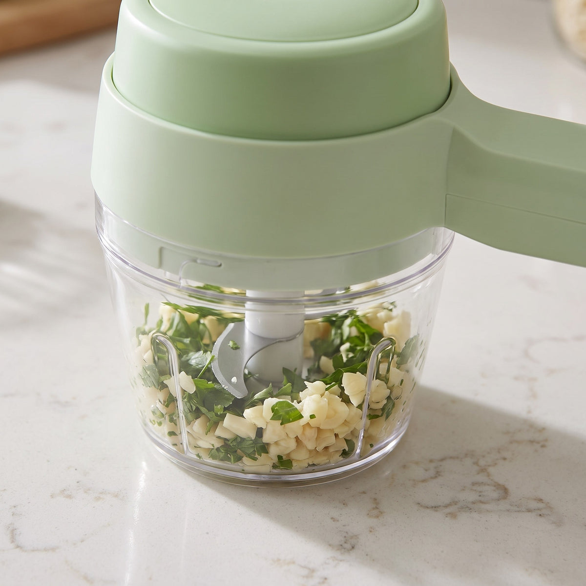 4-in-1 Compact Food Chopper and Whisk with Cleaning Brush - close-up of the stainless steel blades in the clear bowl
