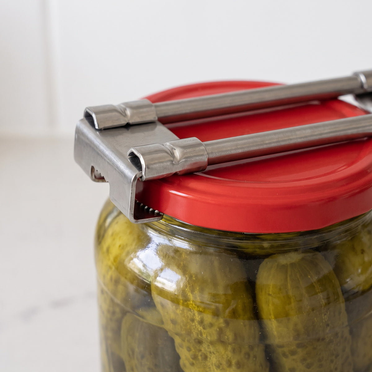 Adjustable Stainless Steel Jar Opener with Wide Size Range - close-up of the toothed steel clamp gripping a lid