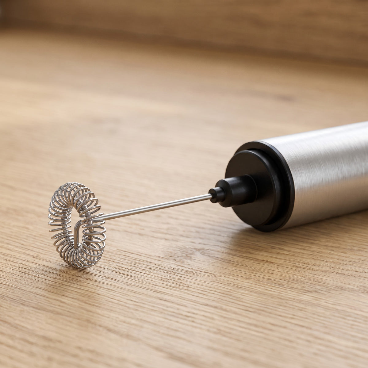 Battery-Operated Handheld Milk Frother with Detachable Head - close-up of the coiled whisk head and brushed metal body