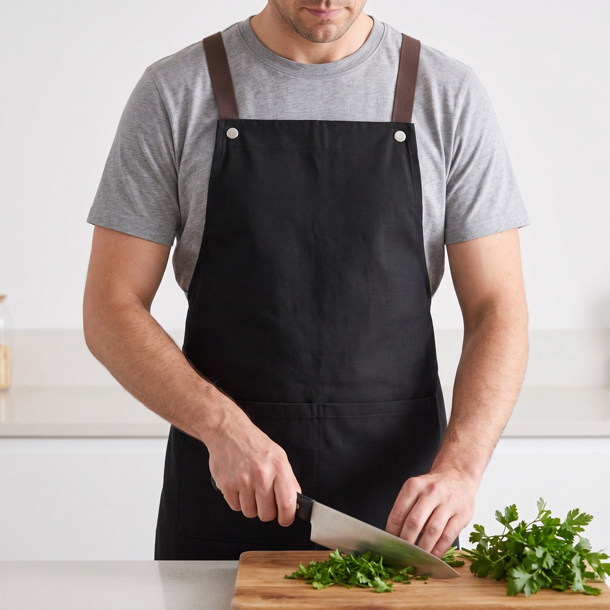 Cross-Back Kitchen Apron with Front Pockets and Waist Tie in use, worn while chopping parsley at the counter
