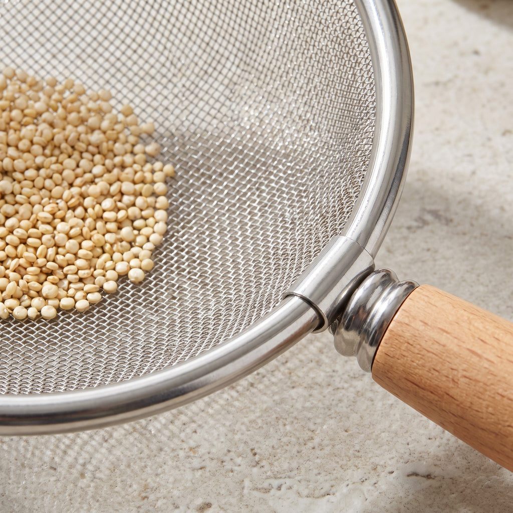 Fine Mesh Stainless Steel Strainer with Wood Handle and Resting Rim - close-up of the fine stainless steel mesh holding quinoa beside the wood handle