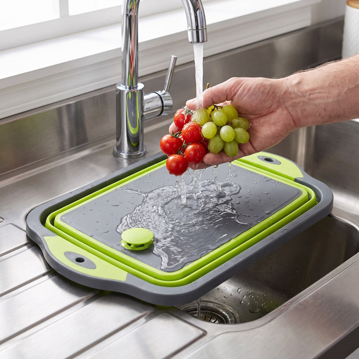 Foldable Cutting Board with Drain Hole for Rinsing and Pouring in use, rinsing tomatoes and grapes at the sink