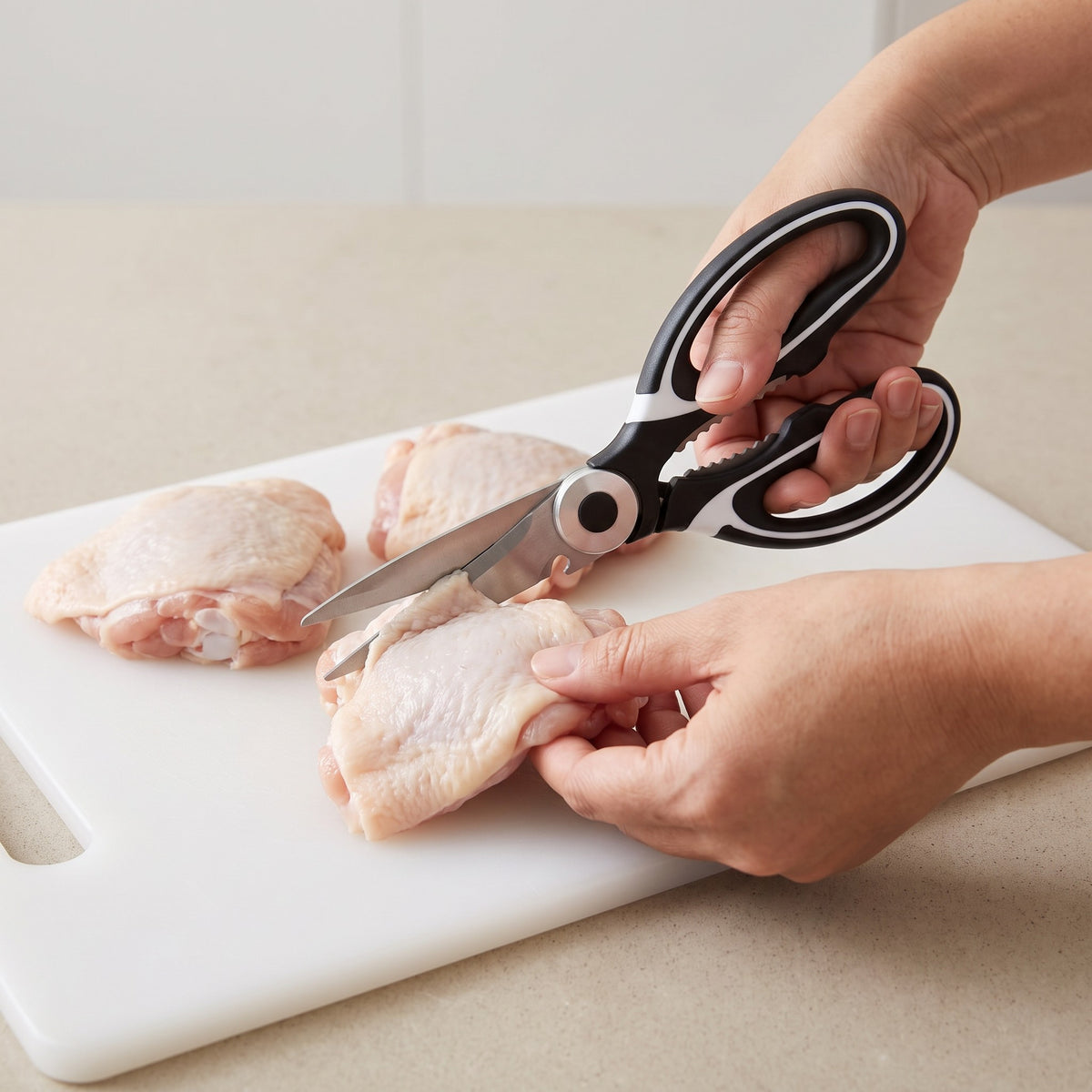 Heavy-Duty Kitchen Scissors with Stainless Steel Blades in use, trimming raw chicken thighs on a cutting board