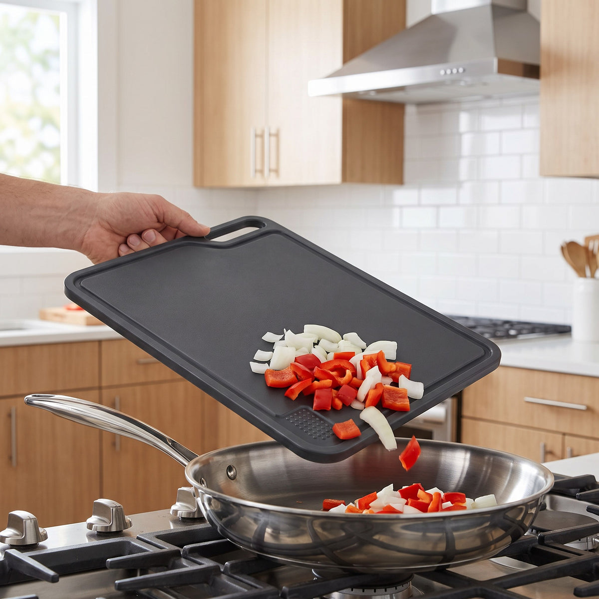 Large Non-Slip Plastic Cutting Board with Side Handles in use, sliding chopped peppers and onions into a pan