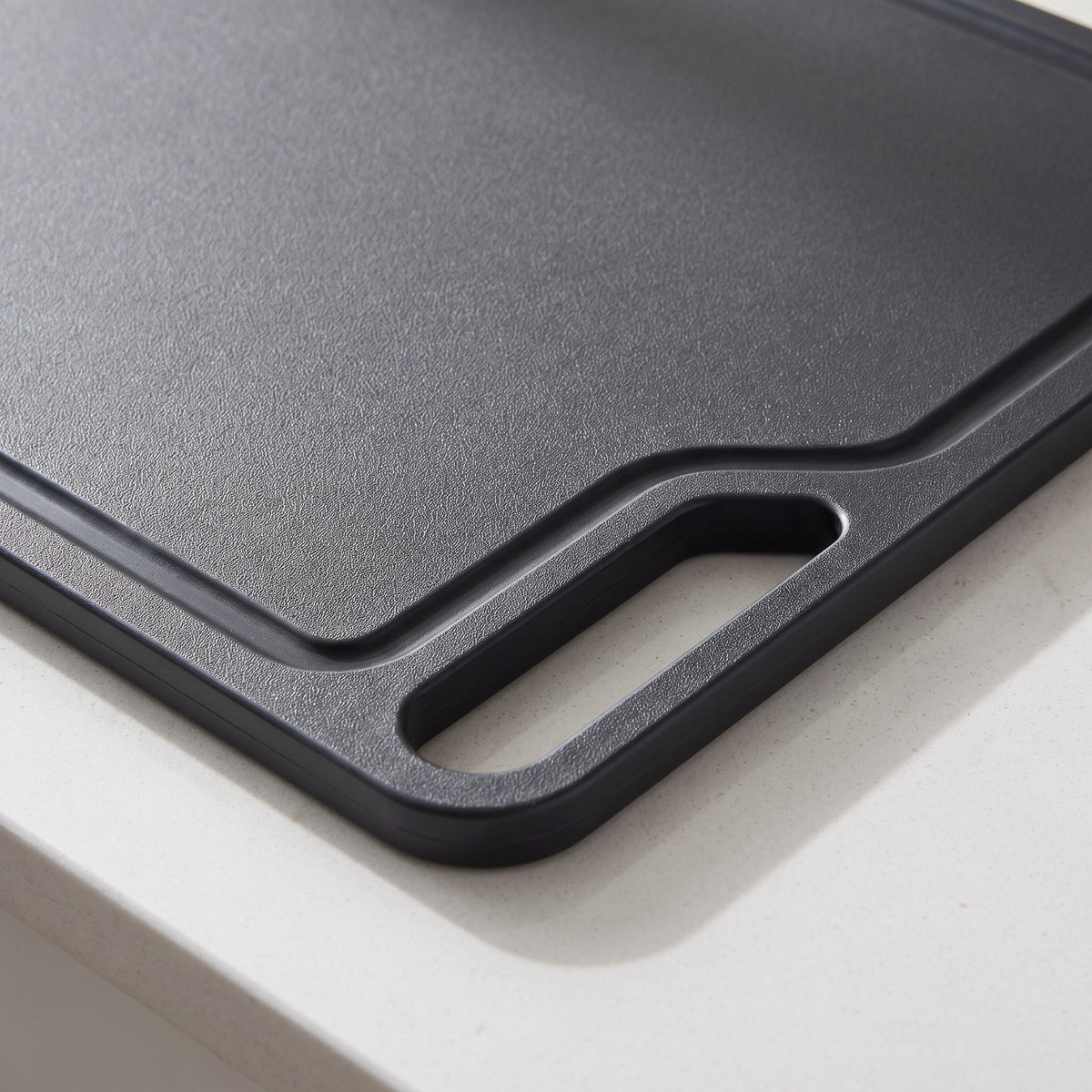 Large Non-Slip Plastic Cutting Board with Side Handles - close-up of the textured non-slip surface and handle