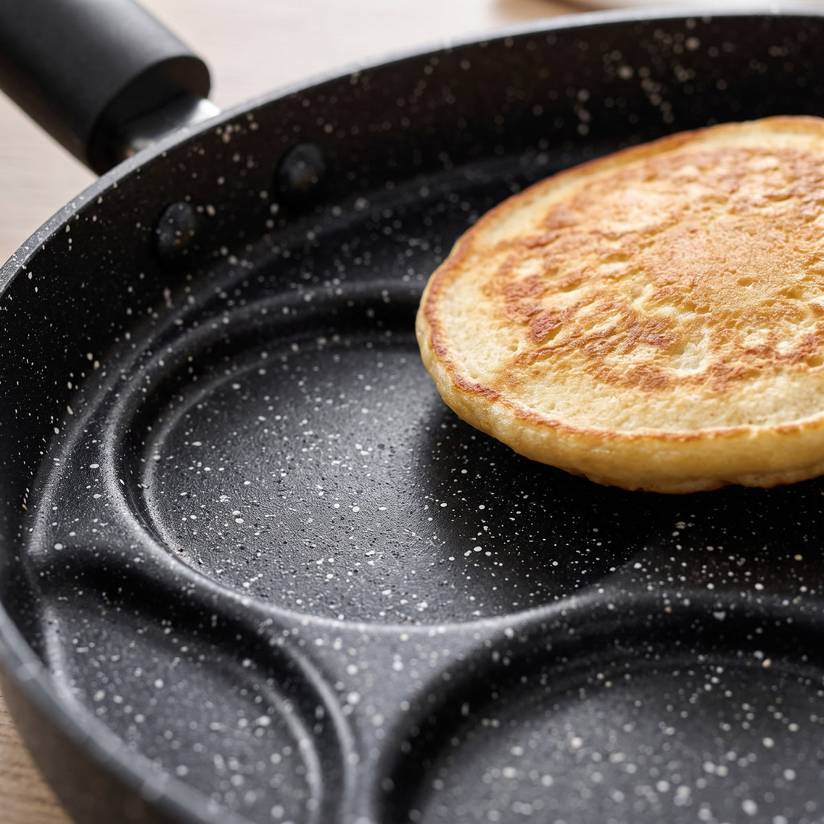 Multi-Cup Non-Stick Pancake Pan for Eggs and Blinis - close-up of the speckled non-stick cups with a golden pancake