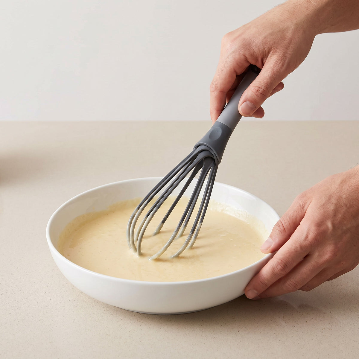 Non-Scratch Flat Roux Whisk with Long Handle in use, whisking pancake batter in a wide bowl