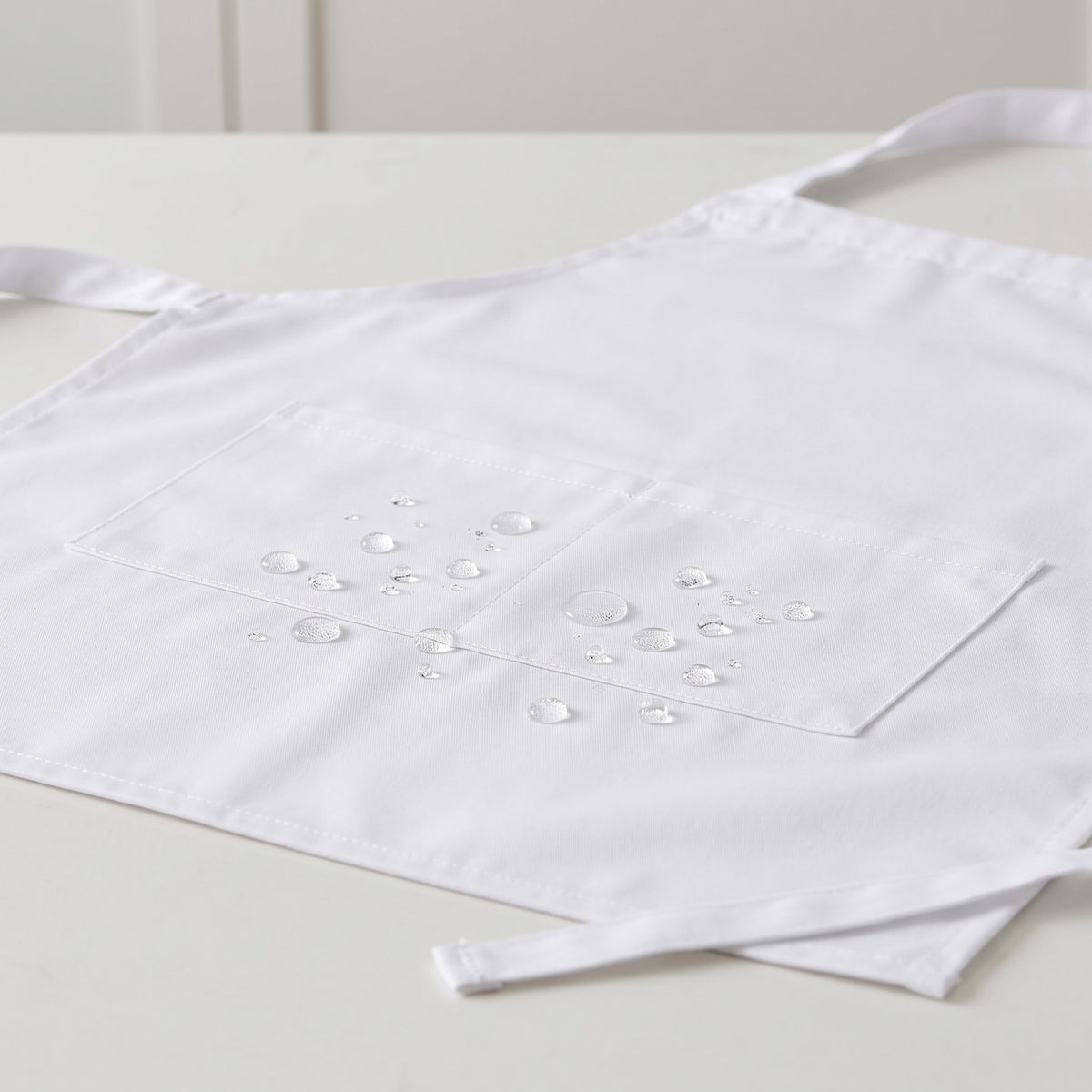 Relaxed-Cut Waterproof Bib Apron with Pockets - close-up of water beading on the waterproof fabric and pocket stitching