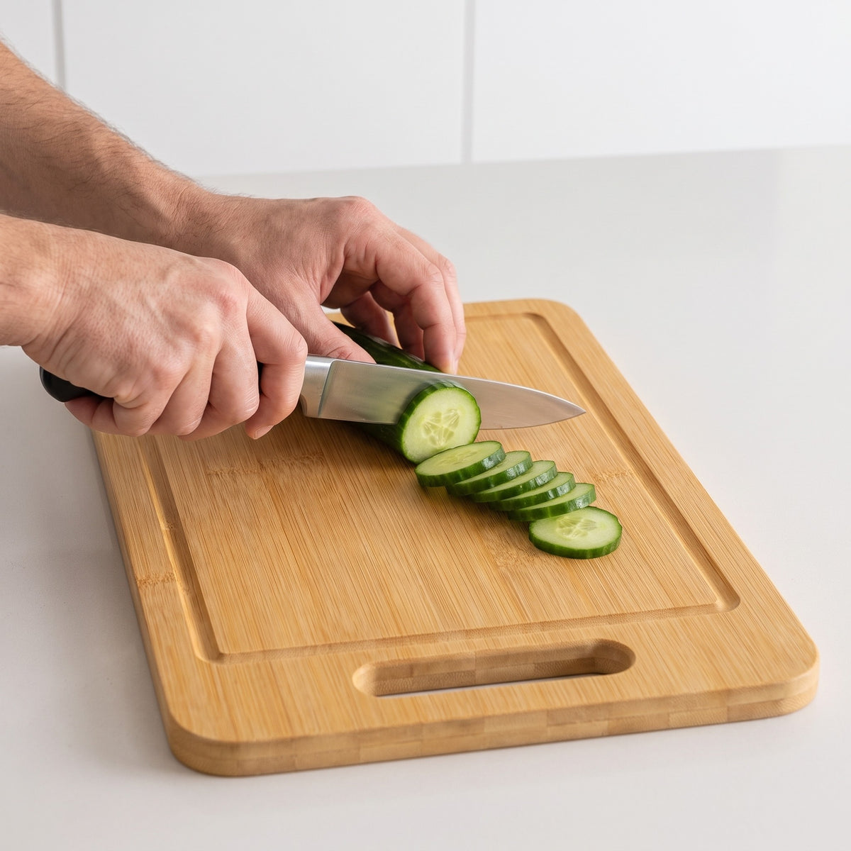 Reversible Bamboo Cutting Board with Juice Groove in use, slicing a cucumber