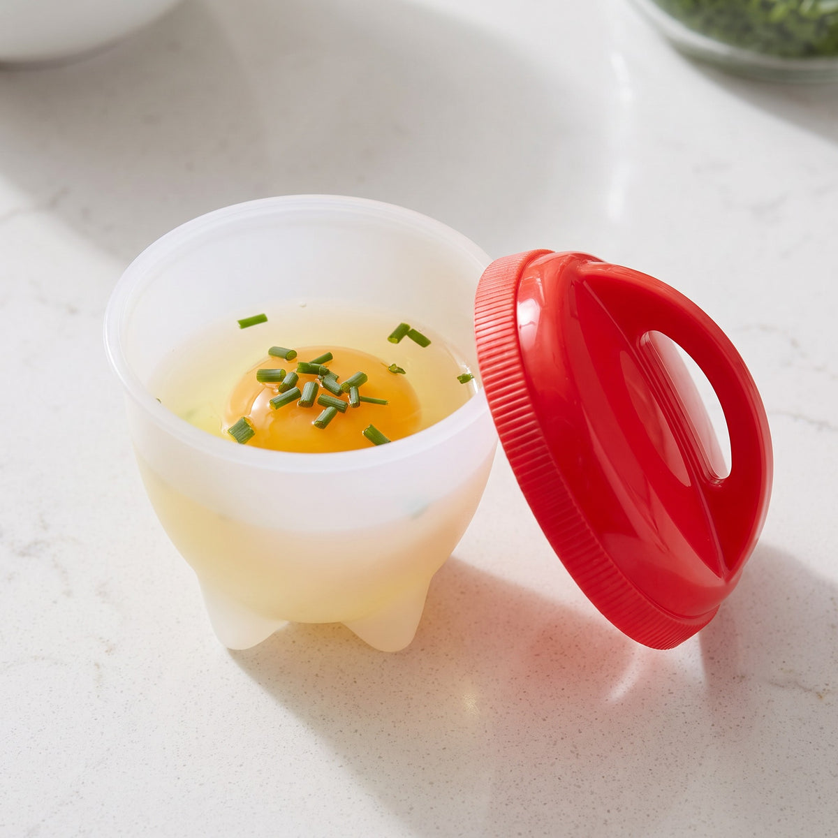 Shell-Free Egg Cooker Cups for Breakfast and Meal Prep - close-up of a cup with a cracked egg and chopped chives