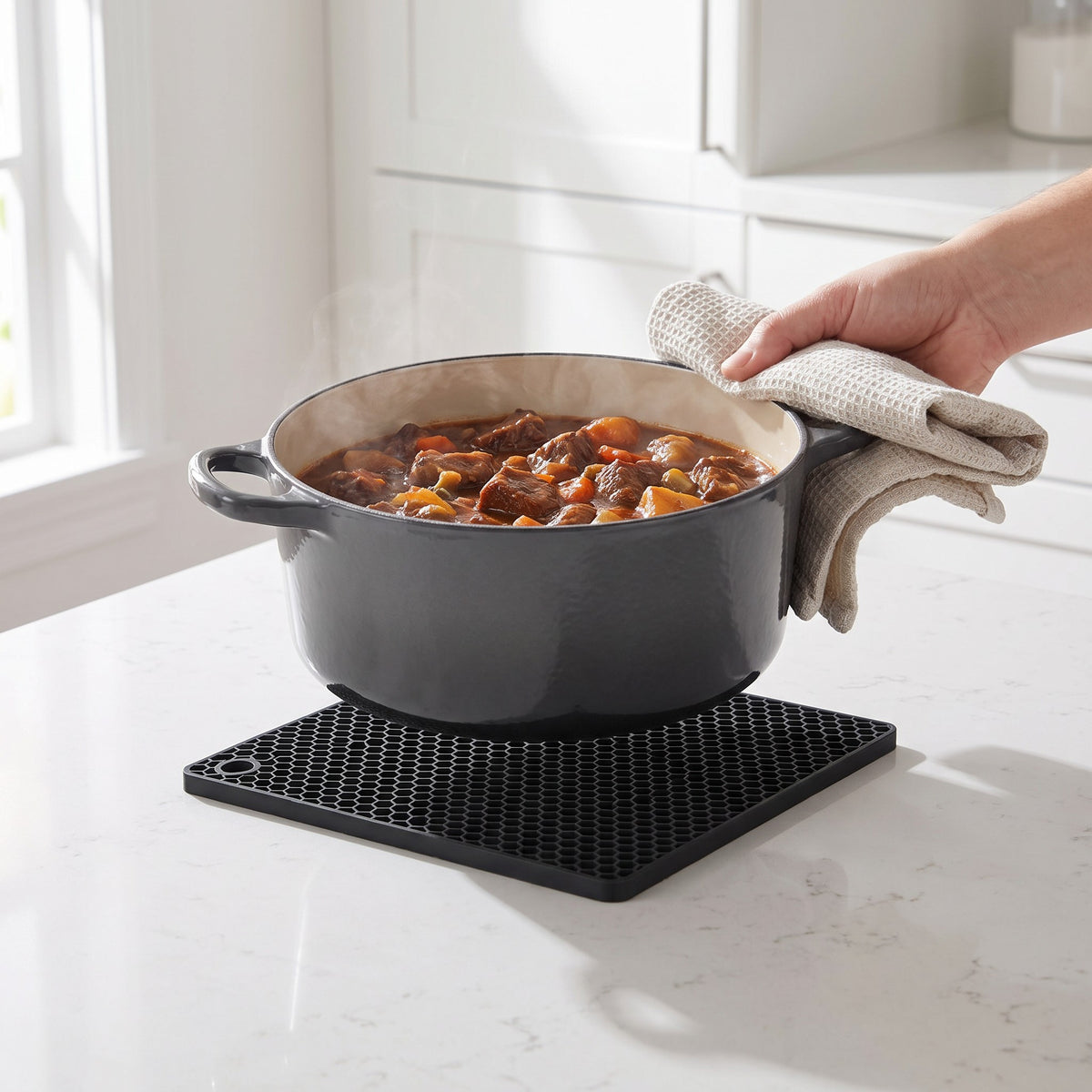 Square Silicone Trivet Mat with Honeycomb Grip in use, holding a hot Dutch oven of stew on a stone countertop