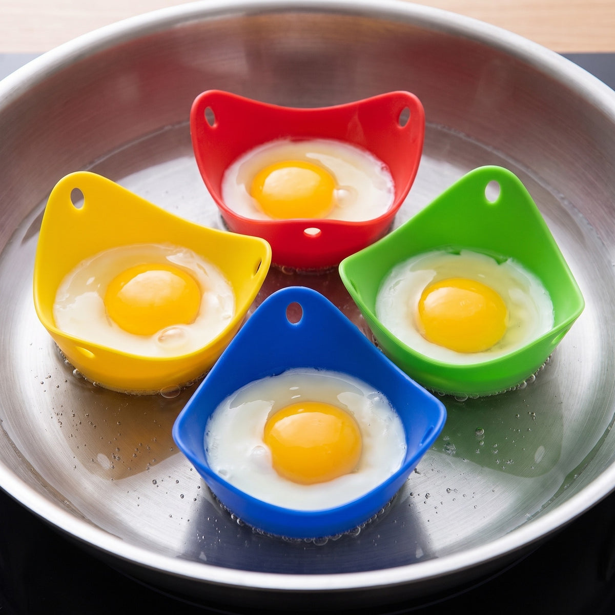 Stackable Egg Poacher Cups Set for Eggs Benedict and Brunch in use, poaching four eggs in a pan of simmering water
