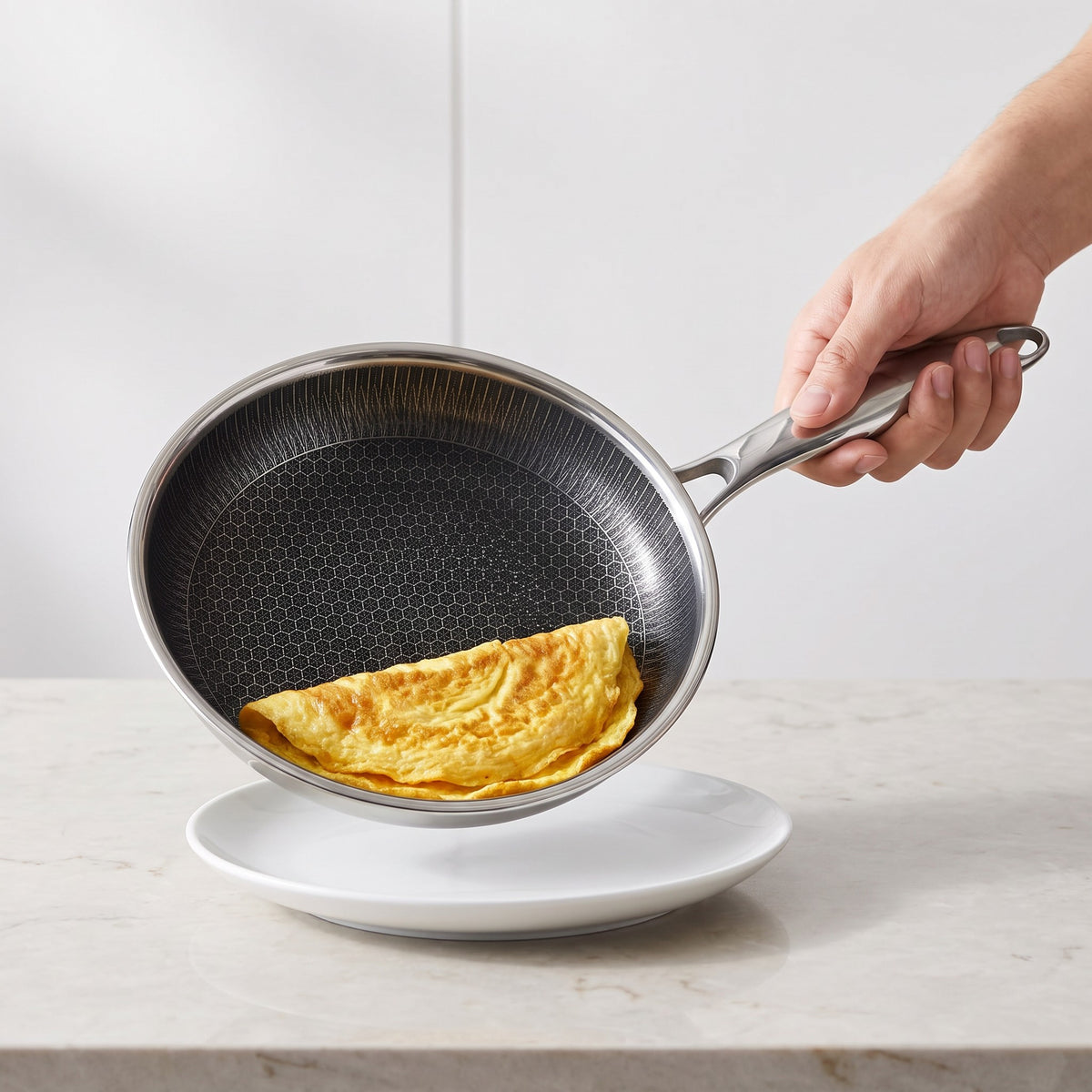 Stainless Steel Honeycomb Non-Stick Frying Pan with Removable Handle in use, sliding an omelette onto a plate