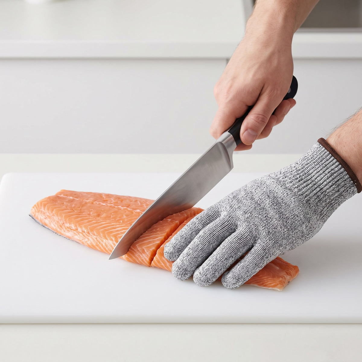 Stainless Steel Mesh Cut-Resistant Glove for Butchering and Filleting in use, steadying a salmon fillet while slicing