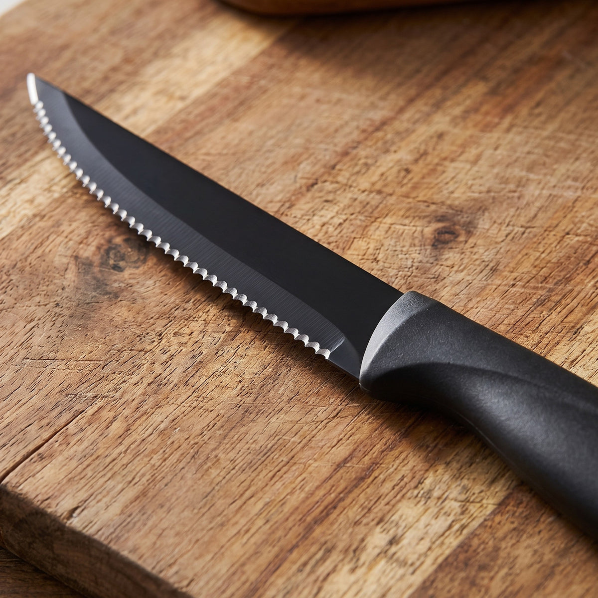Stainless Steel Steak Knife Set with Scratch-Resistant Blades - close-up of the serrated black blade and ergonomic handle