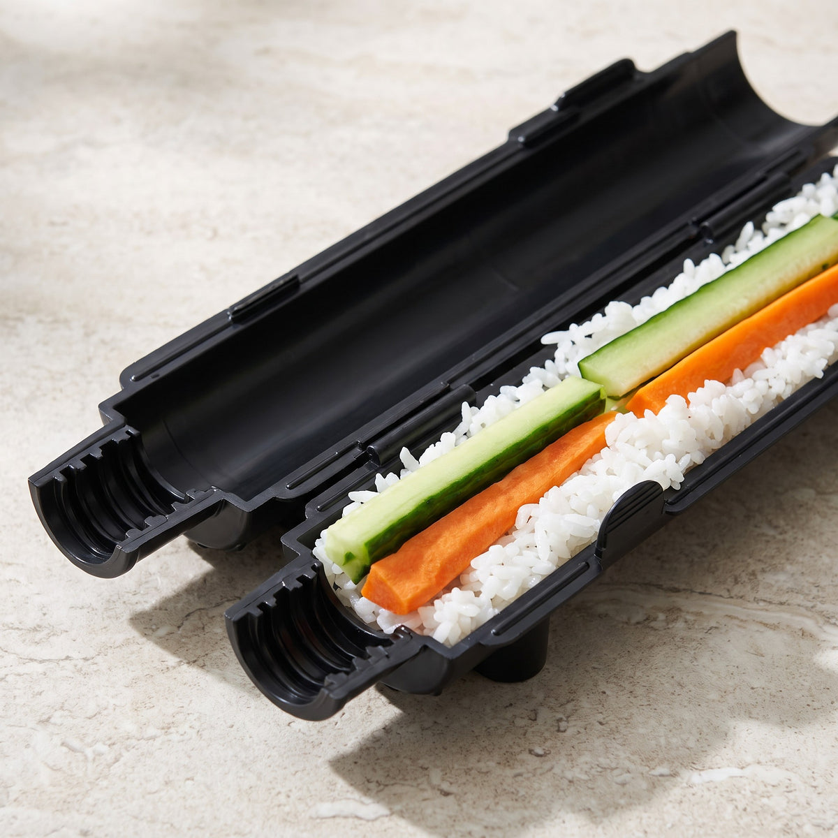 Tube-Style Sushi Bazooka Roll Maker for Maki and California Rolls - close-up of the open black tube halves filled with rice, cucumber and carrot